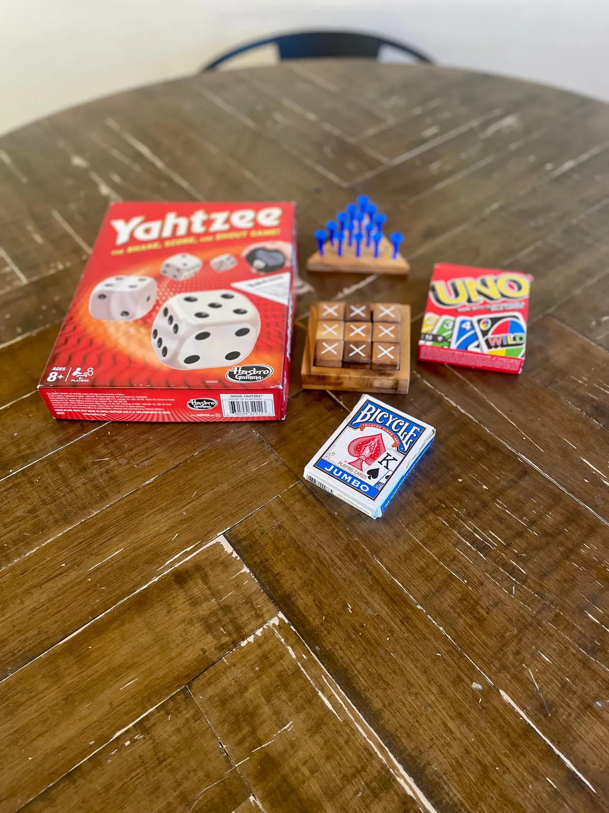 An inviting interior scene centers on a round table with classic board games—Yahtzee, UNO, and more—set up for a night of fun. The setting is warm and nostalgic, with hints of comfortable furnishings in the background, suggesting a space where families can reconnect after a day of exploring.