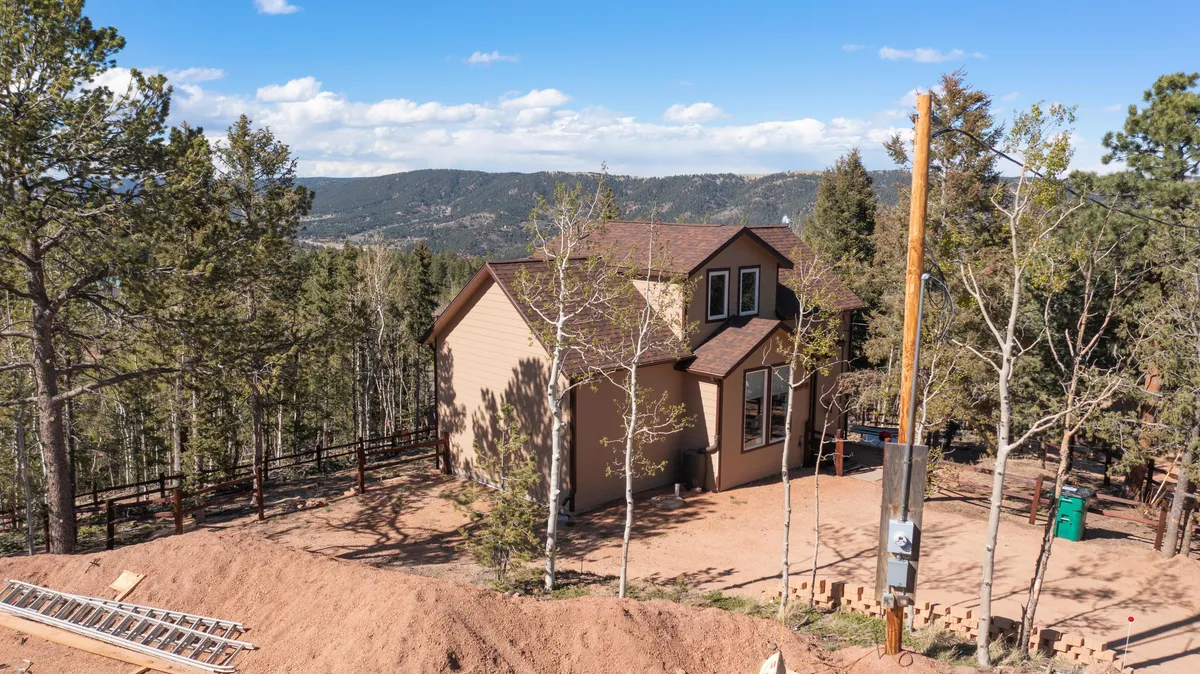 This exterior image features the house nestled among tall trees with a stunning mountain view in the background. The setting is serene, capturing the natural landscape and the sense of seclusion, perfect for a family escape. The house's porch invites guests to step outside and embrace nature, suggesting the beginning or end of an adventurous day.